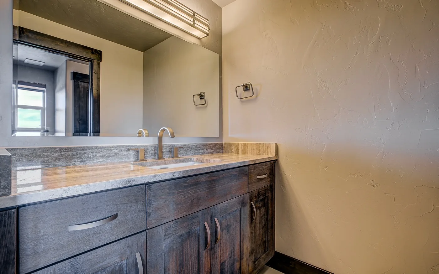 A long custom bath vanity in stained wood with a stone top